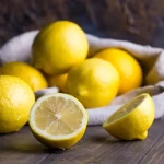 Citrons jaunes entiers et coupés sur une planche en bois illustrant les bienfaits du citron