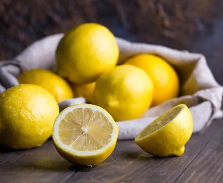 Citrons jaunes entiers et coupés sur une planche en bois illustrant les bienfaits du citron