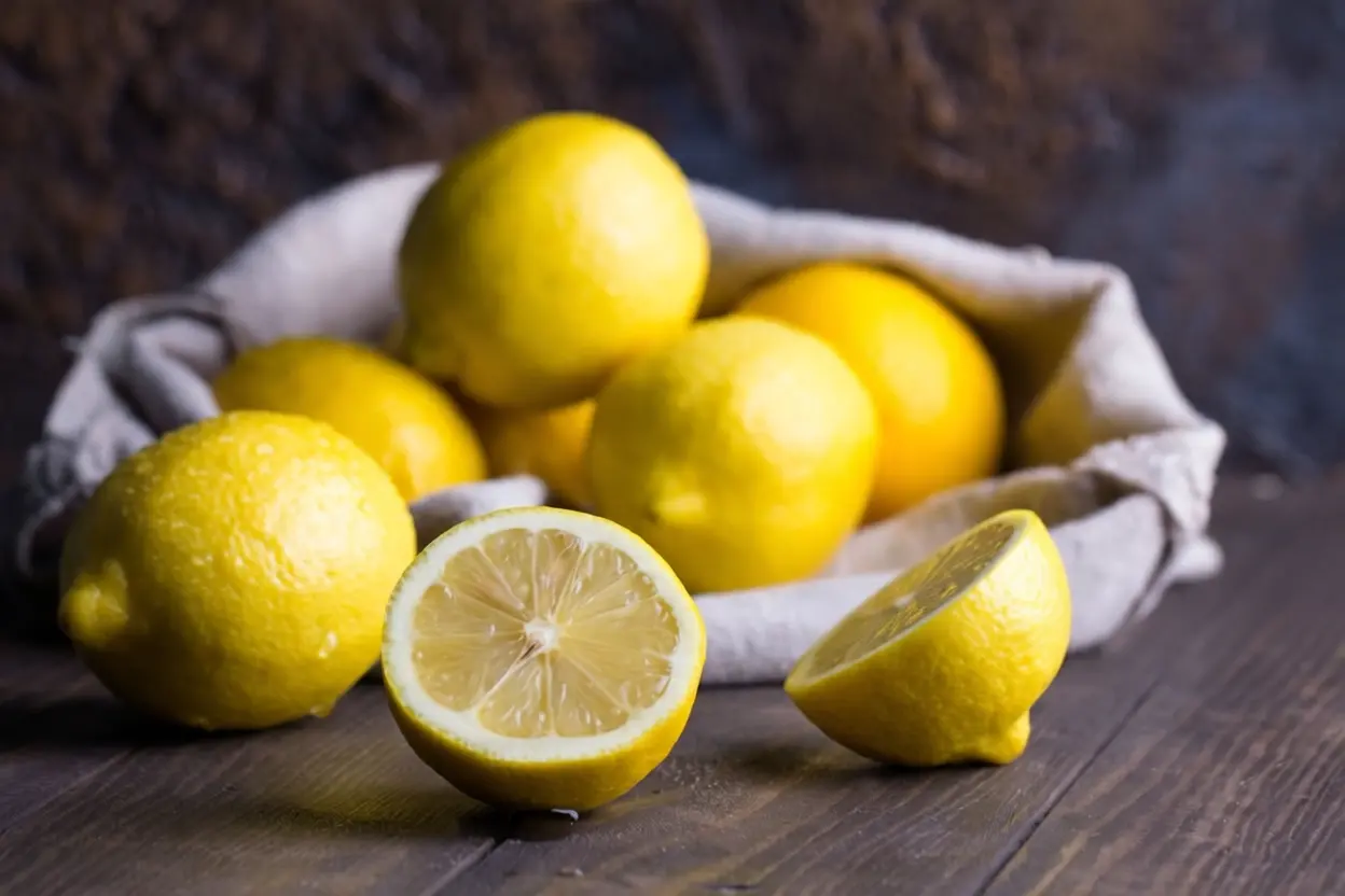 Citrons jaunes entiers et coupés sur une planche en bois illustrant les bienfaits du citron