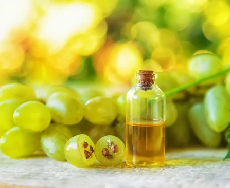 Cuillère d'huile de pépins de raisin posée sur une table avec des raisins frais