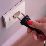 Installation d'une prise en saillie blanche fixée sur un mur avec goulotte électrique apparente