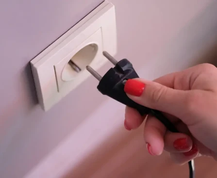 Installation d'une prise en saillie blanche fixée sur un mur avec goulotte électrique apparente