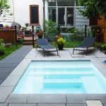 Mini piscine installée dans un jardin aménagé avec terrasse en bois