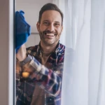 Personne nettoyant une vitre avec un chiffon et une solution d'ammoniaque