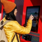 Voyageur consultant les prix des billets de train sur un écran de gare