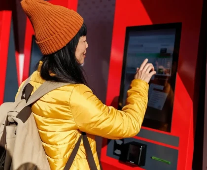 Voyageur consultant les prix des billets de train sur un écran de gare